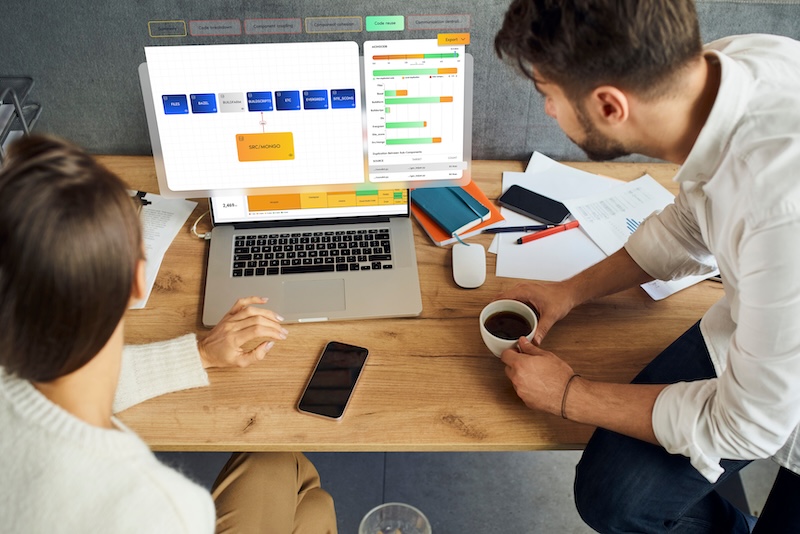 This is aa mockup of Two people collaborating at a desk with a laptop displaying of architecture & code quality.