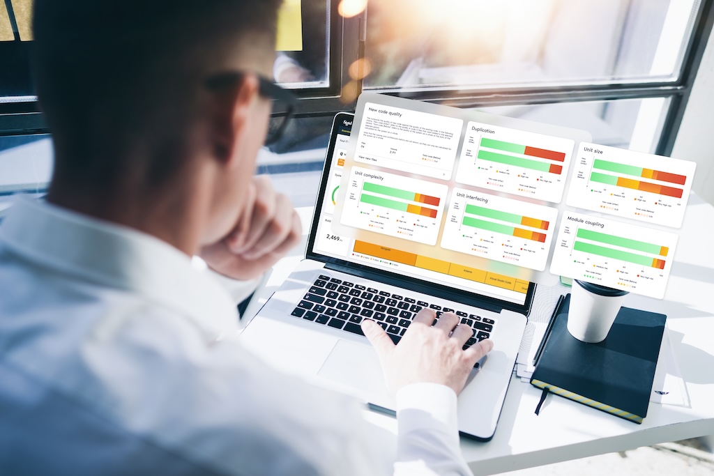 This is a mockup of person working on a laptop displaying software metrics of the maintainability feature of Sigrid platform .