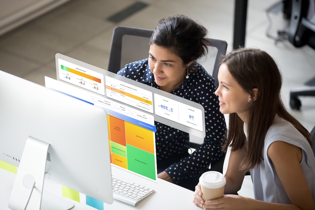 This is a mockup image of two women in an office looking at the SIG's maintainability feature on computer screen displaying colorful charts and data.