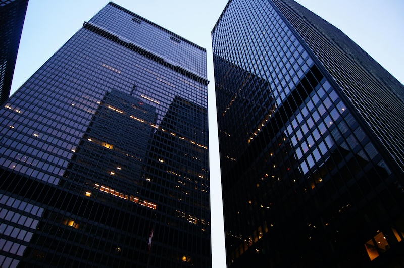 A shot of tow corporate skyscrapers taken from ground level to create a towering and impressive view.