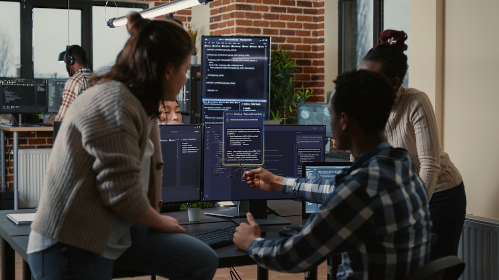 A development team reviewing code and maintainability findings on a computer screen in an office setting.