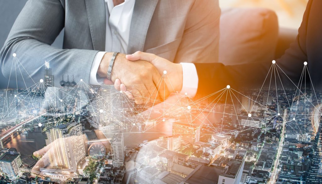 Two people in suits shaking hands over a digital cityscape with network lines and nodes.