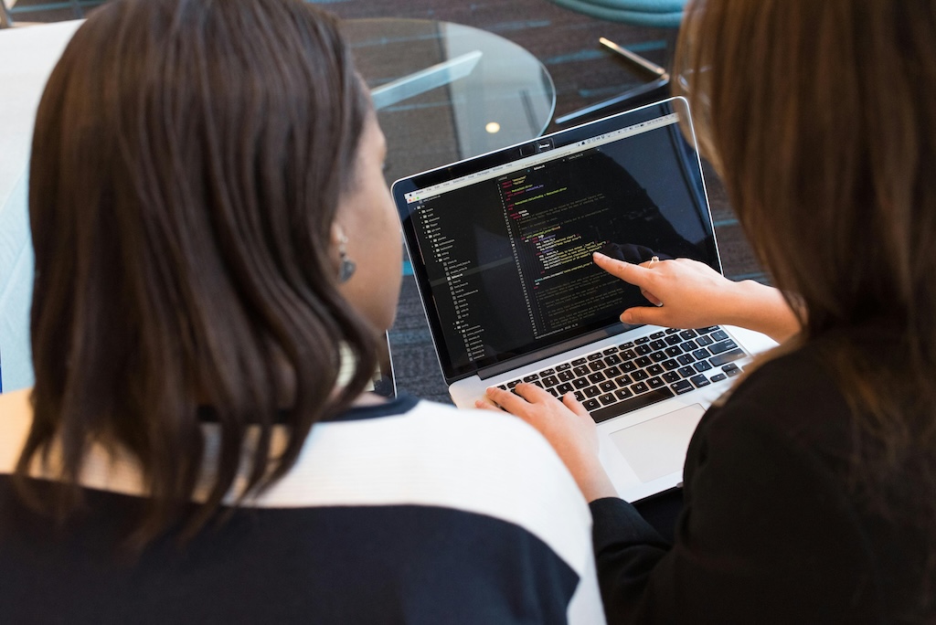 A female It leader checking the software quality of code with her software development team member.