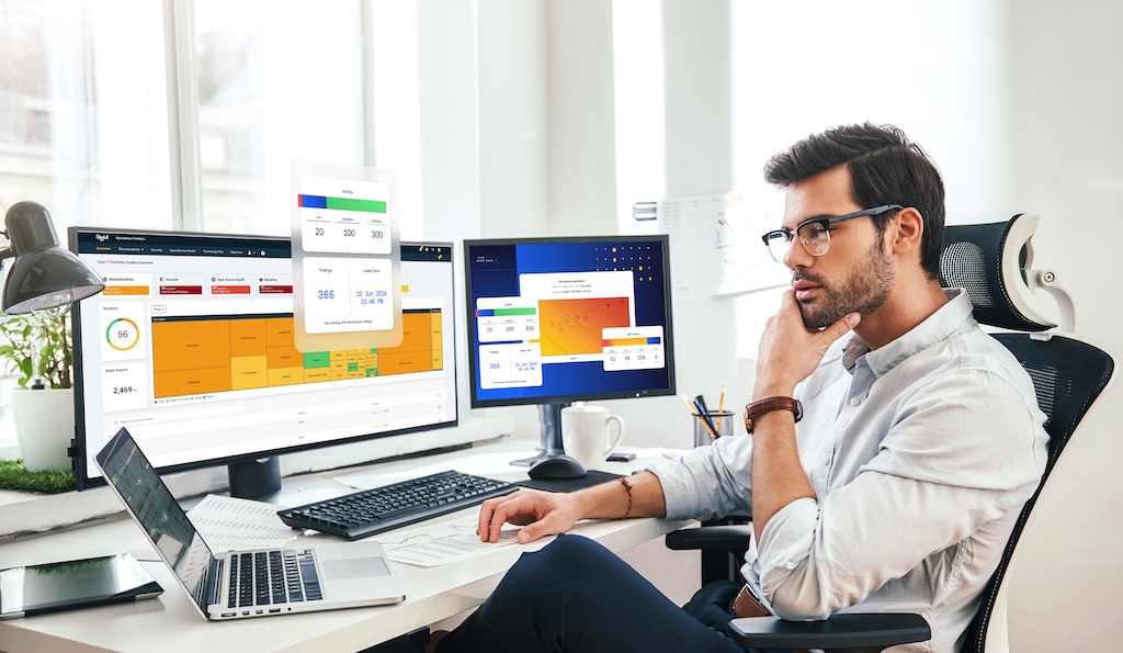 This ia mockup image of a man in an office works at a desk with multiple computer screens displaying data and charts of Sigrid's Security feature.