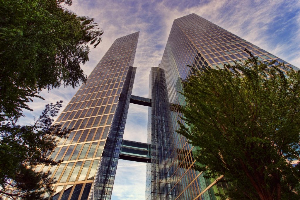Tall corporate skyscraper with greenery.
