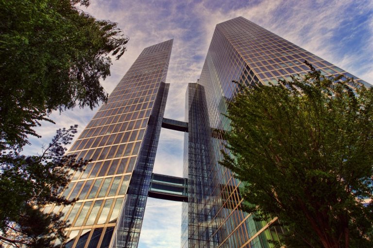 Tall corporate skyscraper with greenery.