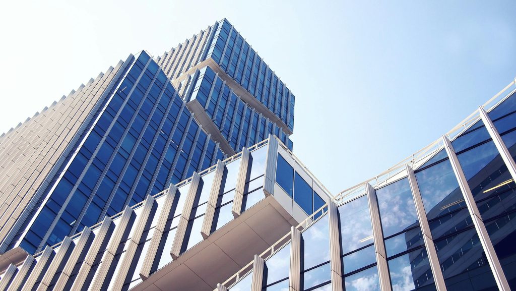 Image of a modern glass and metal building with reflective blue-tinted windows under a clear sky.
