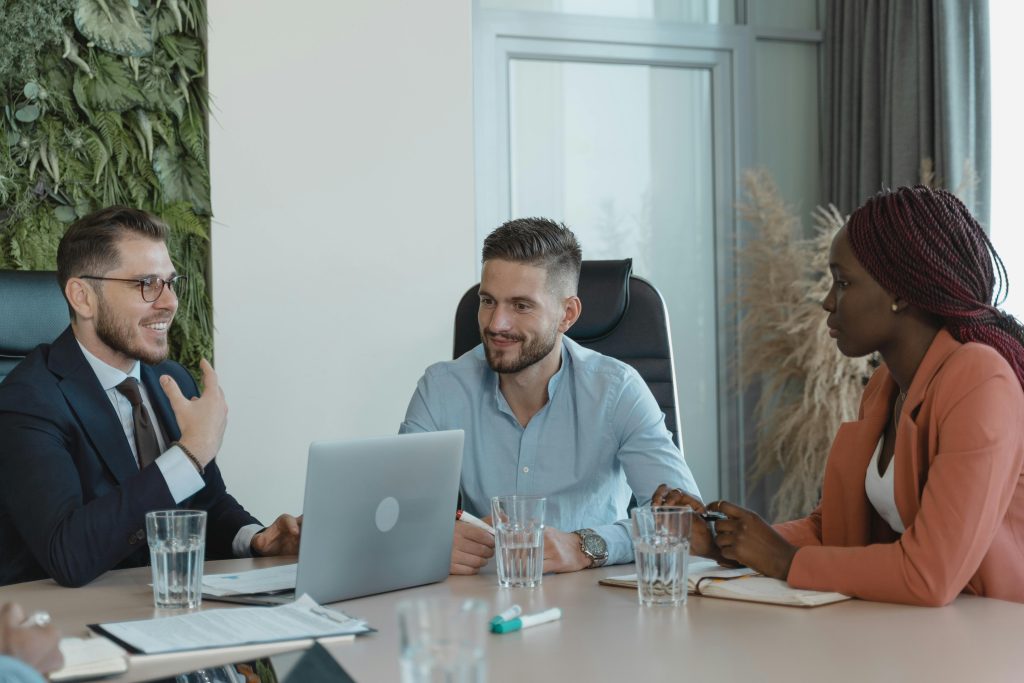 3 colleagues having a discussion in a green and modern office setting.