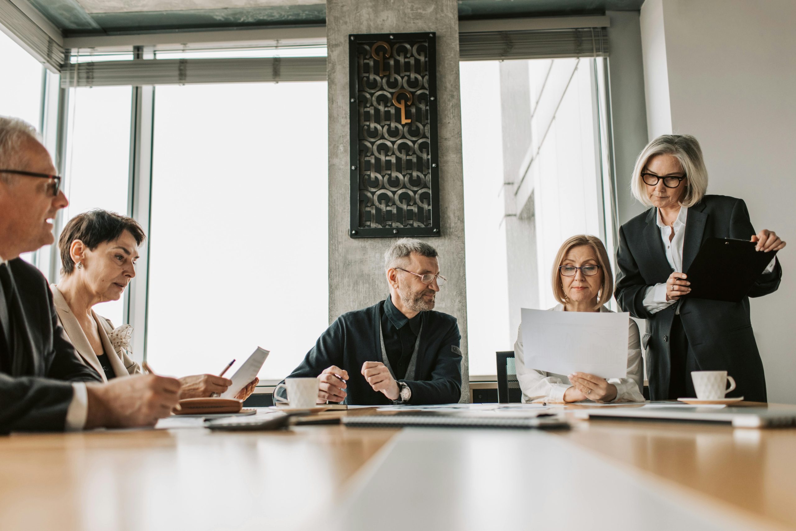 A group of five colleagues in a conference room having a discussion.