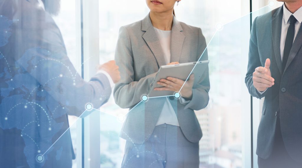 Three professionals in suits engaging in a conversation with a soft digital overlay.
