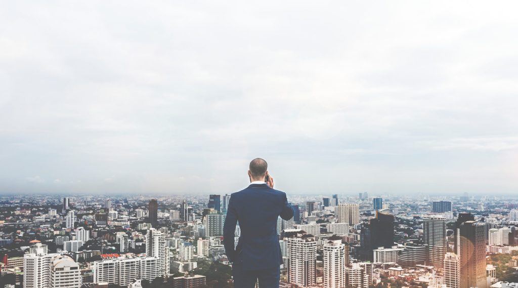 Image of a man talking on a phone facing a city skyline