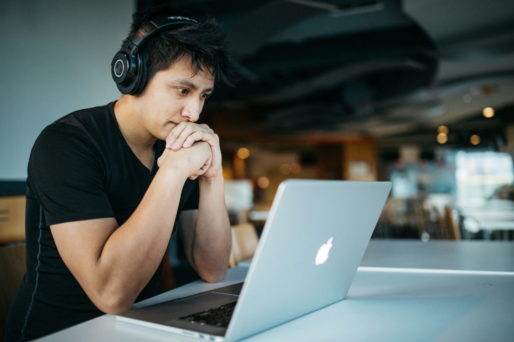 Image of a person wearing headphones, focusing on a laptop at a table.